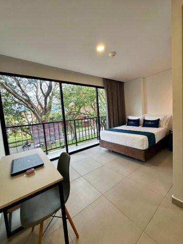 a bedroom with a bed and a desk with a laptop at Hotel ECO 44 in Medellín