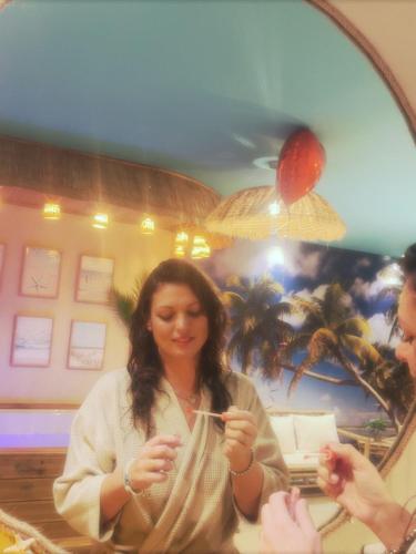 a woman is looking at her reflection in a mirror at Les Spas de la Mer, Appart&Spa Aloha, 100m de la plage, Plein cœur du Grau in Le Grau-du-Roi