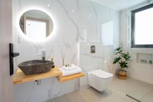 a bathroom with a sink and a toilet and a mirror at Oriens Villas in Palaiokhóri