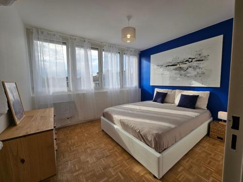 une chambre avec un grand lit avec un mur bleu dans l'établissement Jolie maison à guilherand-granges, à Guilherand