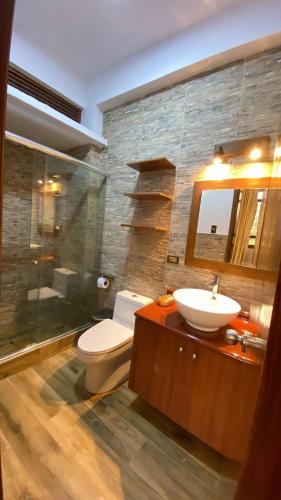 a bathroom with a sink and a toilet and a mirror at Tantiri River Resort in Puerto Maldonado