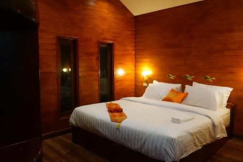 a bedroom with a large white bed with wooden walls at Ruen Tai Boutique in Nai Yang Beach