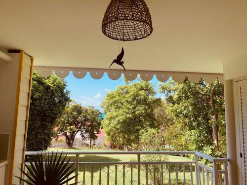 a balcony with a window with a bird perched on it at TI KAZ DOUDOU - village de vacances bord de mer in Sainte-Anne