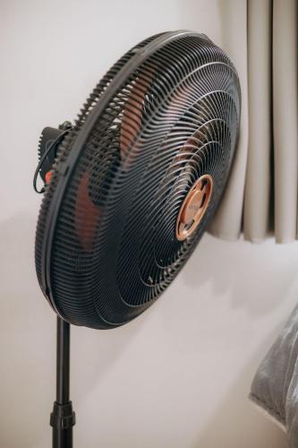 a black fan is on a stand next to a curtain at Residencial Mizinho Ap2 in Florianópolis