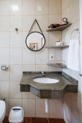 a bathroom with a sink and a mirror and a toilet at Residencial Mizinho Ap2 in Florianópolis