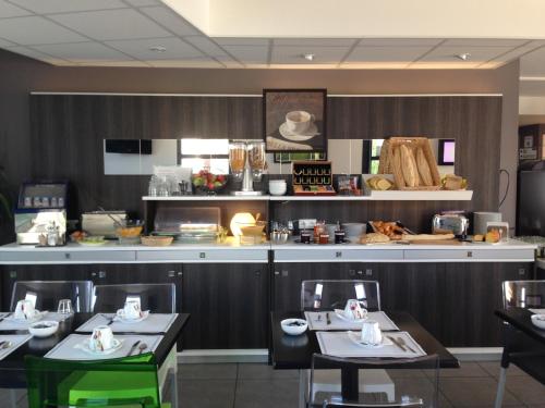 a dining room with two tables and a counter with at The Originals City, Hotel Novella Premium, Nantes Est in Carquefou