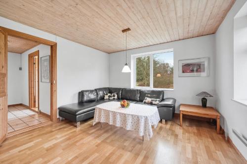 a living room with a black leather couch and a table at Large Pool House With Activity Room Located In Peaceful Surroundings in Frøstrup