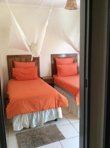 two beds in a room with orange pillows at Tabonina Guesthouse in Livingstone