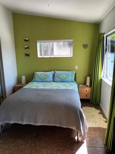 Un dormitorio con una cama y una pared verde. en Island Breeze, en Oneroa