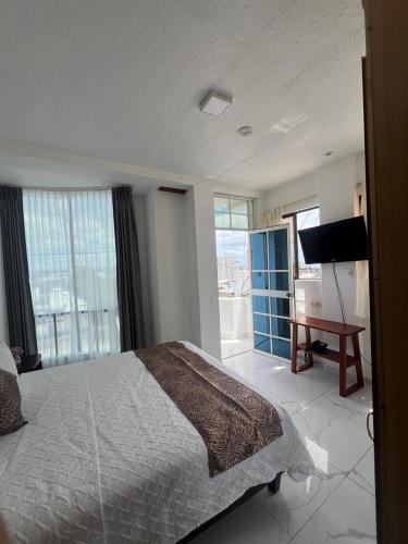 a bedroom with a bed and a flat screen tv at Hostal Carliza in Puerto Ayora