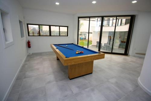 a room with a pool table in a room with windows at Requinte House in Nogueira de Cravo