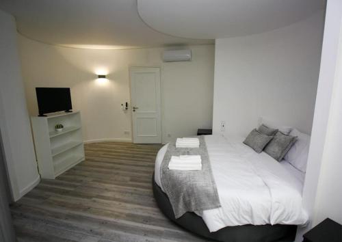 a bedroom with a large white bed and a television at Requinte House in Nogueira de Cravo