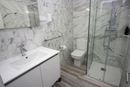 a bathroom with a toilet and a sink and a shower at Requinte House in Nogueira de Cravo
