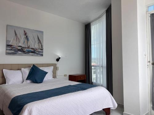 a bedroom with a bed and a large window at Hostal Carliza in Puerto Ayora