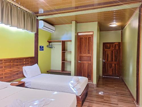 a hotel room with two beds and a door at Infiniti Hotel in Puerto Viejo