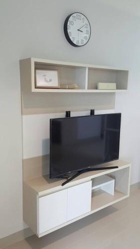 a tv on a shelf with a clock on the wall at JK LIVING Hotel And Service Apartment in Chachoengsao