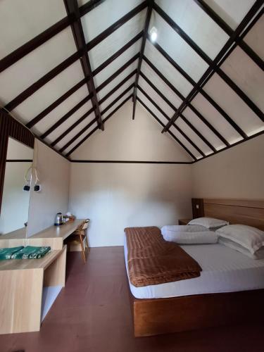 a bedroom with a large bed and a desk at Pondok Roomi Villa in Sembalun Lawang