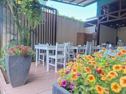 a patio with white tables and chairs and flowers at Infiniti Hotel in Puerto Viejo
