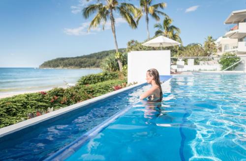 a woman in a swimming pool next to the beach at Tingirana Noosa in Noosa Heads