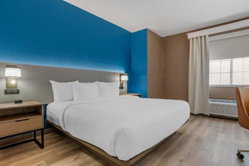 a large bed in a hotel room with a blue accent wall at Comfort Suites Hattiesburg near University in Hattiesburg