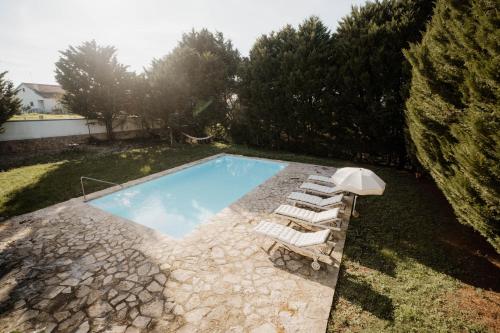 a swimming pool with a group of lounge chairs next to it at NaNa House Ericeira - Yoga & Surf in Santo Isidoro