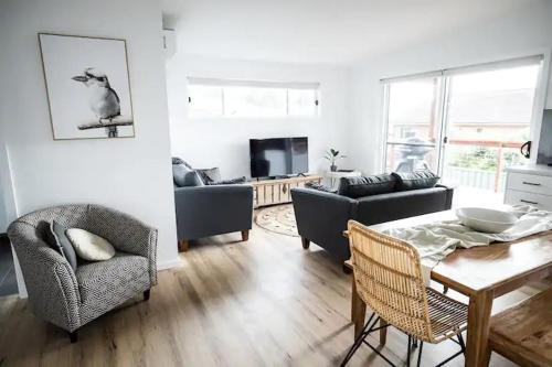 a living room with a couch and a table and chairs at Orion Beach Cottage B - Jervis Bay in Vincentia
