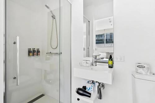 a white bathroom with a sink and a shower at Gibson Mill waterfront warehouse apartment - 204 in Hobart