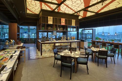 a restaurant with tables and chairs and a bar at Swiss-Belinn Saripetojo Solo in Solo