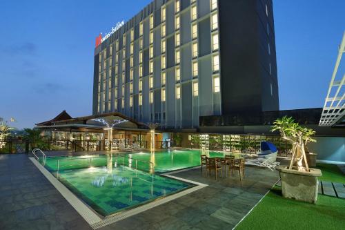 a hotel with a swimming pool in front of a building at Swiss-Belinn Saripetojo Solo in Solo