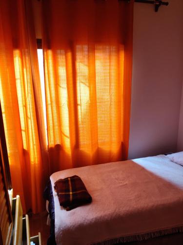 a bedroom with a bed and a window with orange curtains at bungalows in Santa Rosa