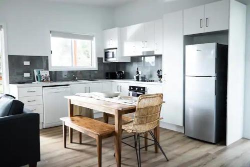 a kitchen with a table and chairs and a refrigerator at Orion Beach Cottage B - Jervis Bay in Vincentia