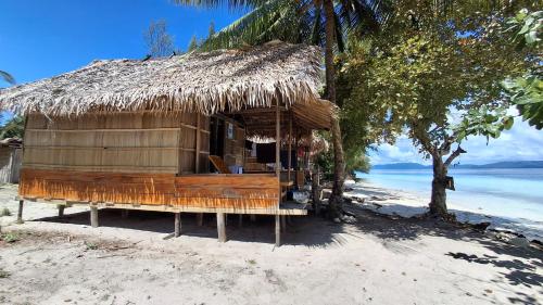 a hut with a straw roof on a beach at Raja Ampat Jousuba Homestay in Minyaifuin