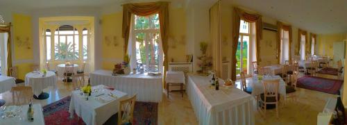 a room with white tables and chairs and windows at Lolli Palace Hotel in Sanremo