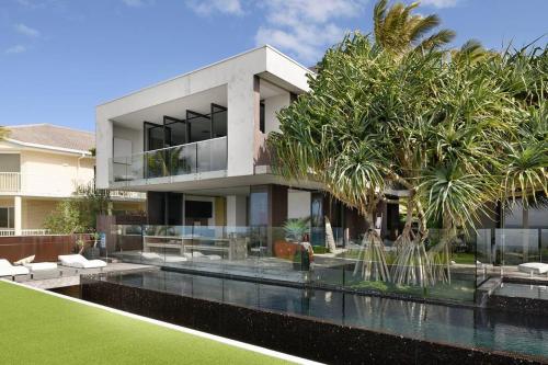 una casa con piscina y palmeras en Eyrie House by Noosa Secret Destinations, en Sunrise Beach