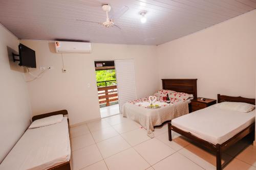 a room with two beds and a tv in it at Tayá Hospedagens in Ubatuba