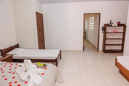 a room with two beds and a table with a plate of food at Tayá Hospedagens in Ubatuba