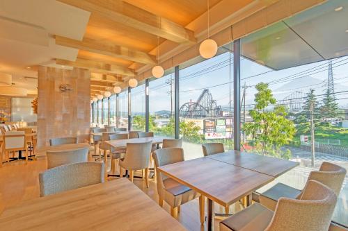 a restaurant with tables and chairs and a large window at HOTEL MYSTAYS Fuji Onsen Resort in Fujiyoshida