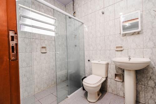 a bathroom with a toilet and a shower and a sink at Tayá Hospedagens in Ubatuba