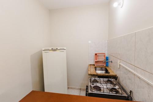 a small kitchen with a stove and a refrigerator at Tayá Hospedagens in Ubatuba