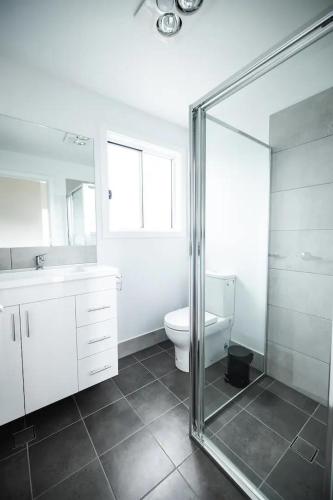 a bathroom with a toilet and a glass shower at Orion Beach Cottage B - Jervis Bay in Vincentia