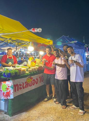 a group of men standing in front of a food stand at Baansrisuthum in Don Sak