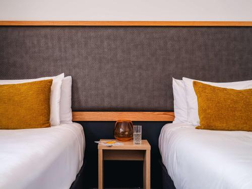 two beds in a hotel room with a side table at Atura Wellington in Wellington