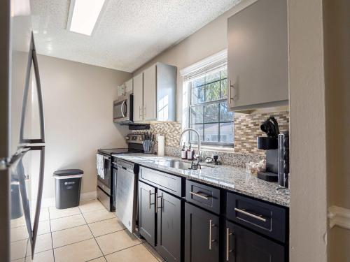 a kitchen with black cabinets and a sink at USF & Busch Gardens Townhome Stay in Tampa