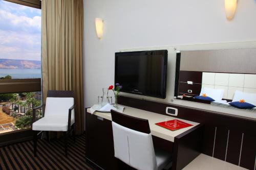 een hotelkamer met een bureau en een grote spiegel bij Golan Hotel in Tiberias
