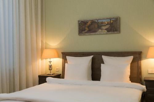 a bedroom with a bed with white sheets and pillows at Wooden Villa APARTMENTS in Jūrmala