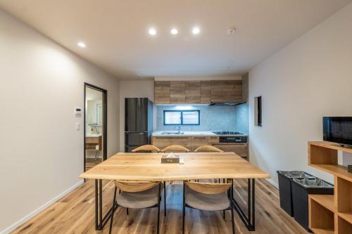 a kitchen and dining room with a wooden table and chairs at Apartment Hotel 11 Villa Hanazonocho in Osaka