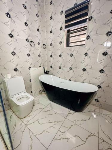 a bathroom with a black and white tub and a toilet at Modern 4-Bedroom Duplex with Home Office Option in Lekki