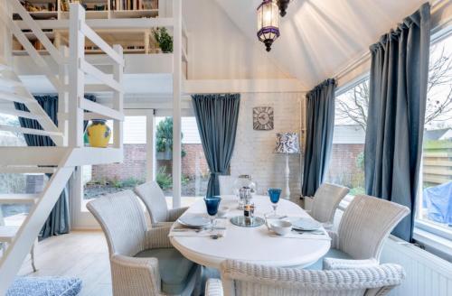 a dining room with a white table and chairs at Huisje Bloemenzee in Noordwijkerhout