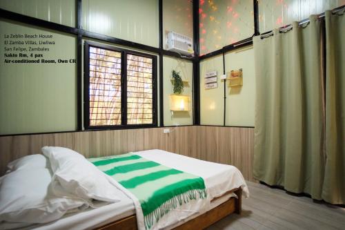 a bedroom with a bed in a room with a window at La Zeblin Beach House in Zambales