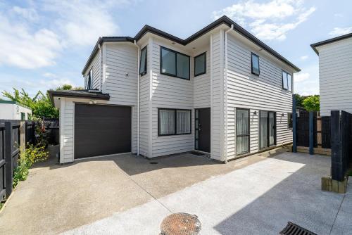 a white house with a garage at Auckland Cornwall Park Home in Auckland